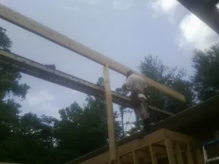 Carpenter setting a ridge beam over a new addition frame — Ice Dam Removal by Roofing Brothers in Peterman