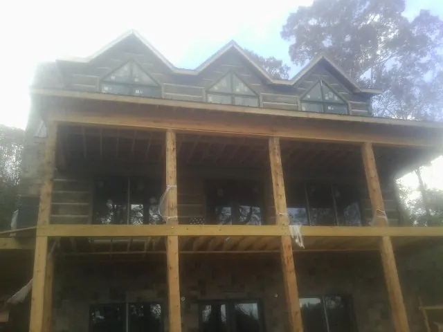 Dormers and porch framing on a large log home under construction — Roof Coating work by our crew in Peterman