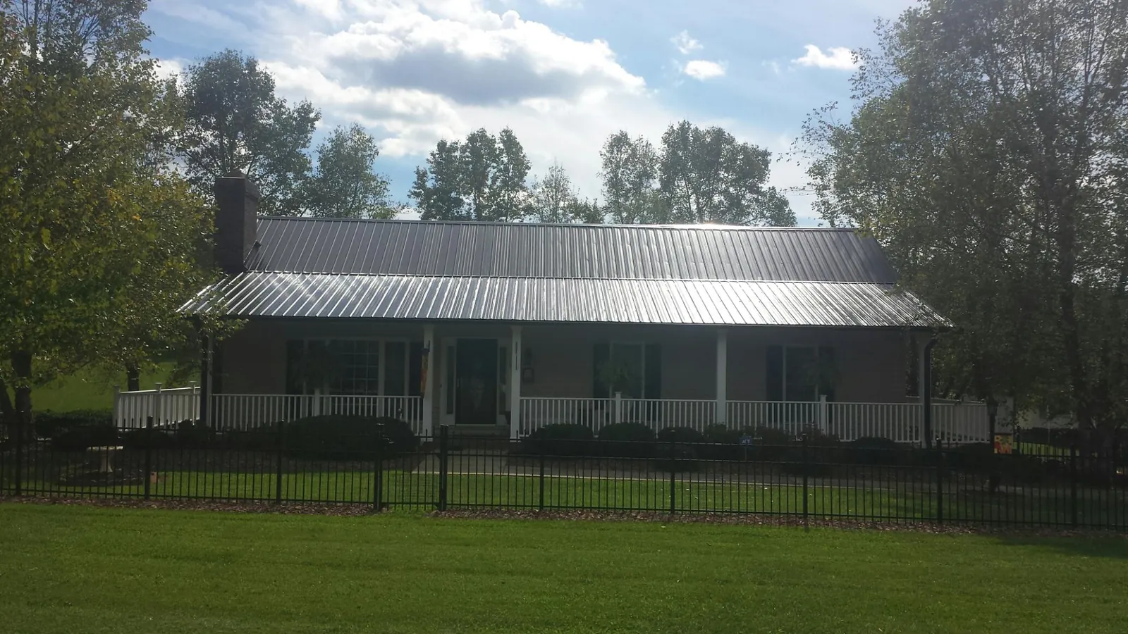 Gray metal roof on a brick ranch with a full width front porch — Gutter Guard Installation work by our crew in Peterman