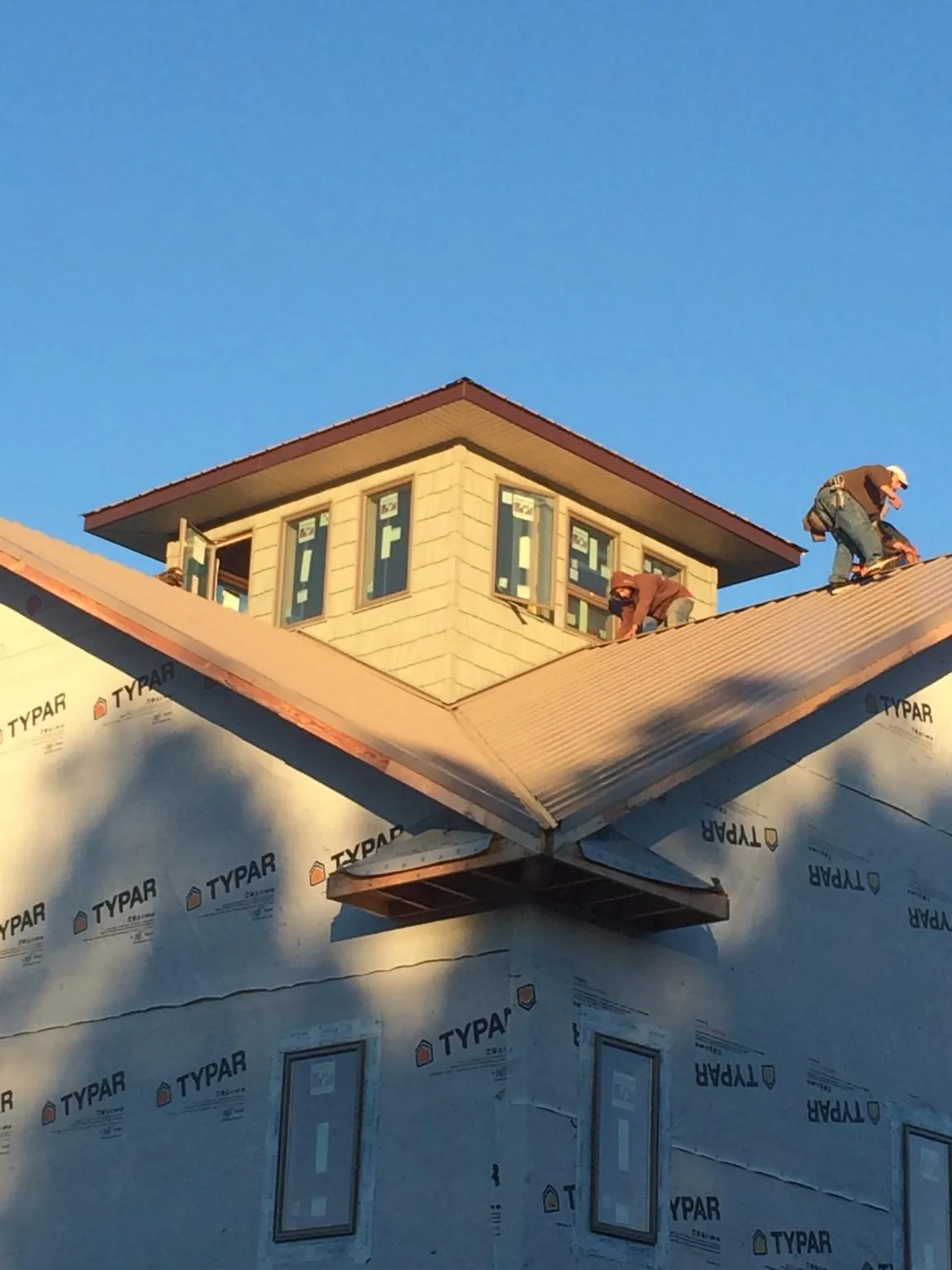 Roofers working around a rooftop cupola on a new metal roof at sunset — Roof Waterproofing in Peterman by Roofing Brothers